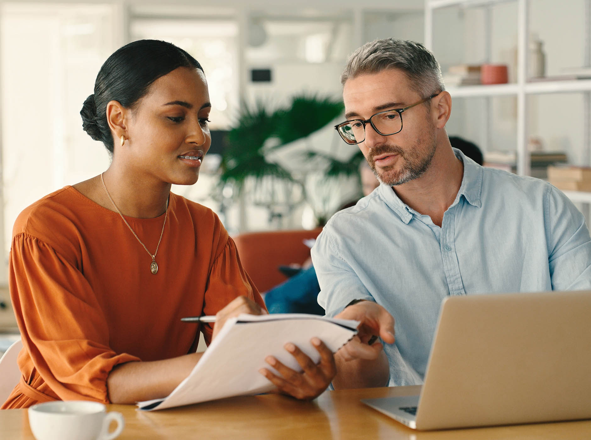 diverse multi-generational business people with paper and laptop discussing a project 